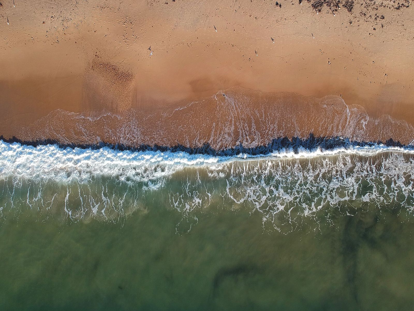 Aerial photo of waves breaking on the sand at Christies Beach.